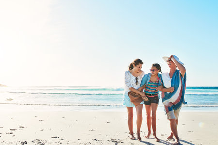 Girls day at the beach. Full length shot of a senior woman spending the day at the beach with her daughter and granddaughter.の写真素材