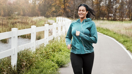On the road to a healthier life. an attractive young woman going for a run in nature.