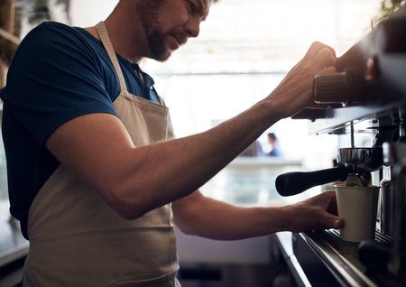 The art of putting together the perfect blend. a barista operating a coffee machine in a cafe.の写真素材