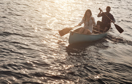 We love adventuring together. a young couple rowing a boat out on the lake.の写真素材