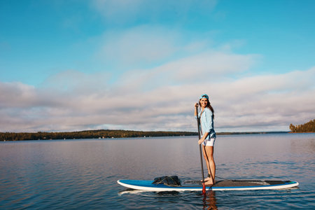This is just the workout I needed. a young woman paddle boarding on a lake.