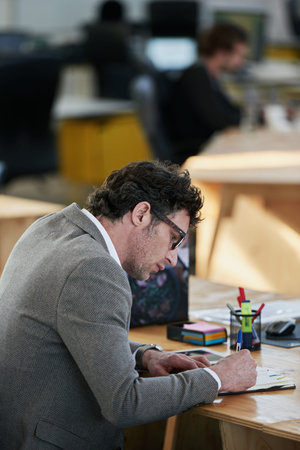 Always write down a good idea. a man working at his desk in an office.