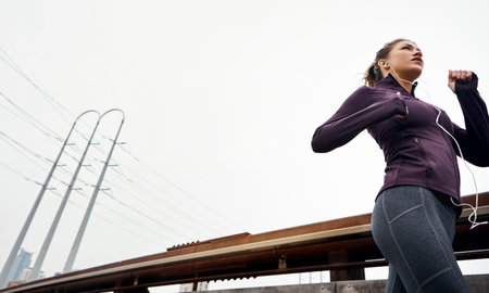 Fast tracking her way to fitness. Low angle shot of an attractive young woman listening to music...