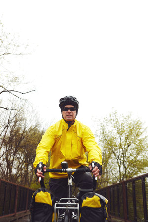 Off the beaten path. a male cyclist enjoying a bike ride on a wet winters morning.の写真素材