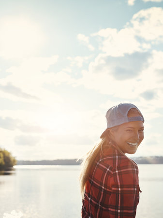 Nature brings me happiness. a happy young woman spending time by the lakeside.の写真素材