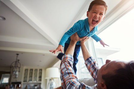 Superboy to the rescue. an adorable little boy and his father playing together on the sofa at home.の写真素材