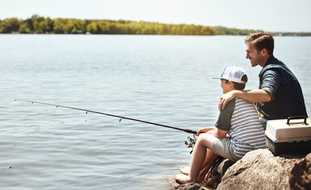 Enjoying their first fishing adventure together. a father and his little son fishing together.の写真素材