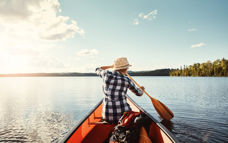 Solitude on the lake. an attractive young woman spending a day kayaking on the lake.の写真素材