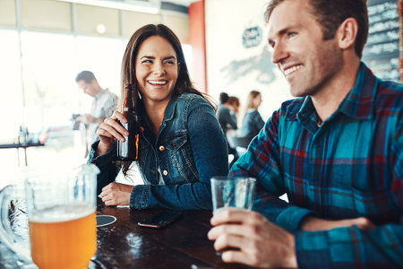 Keeping their dates casual. a happy young man and woman having beers at a bar.の写真素材