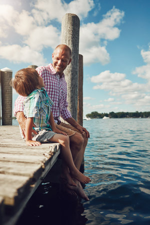 I am with you always. a young father and son on a pier while out by the lake.の写真素材
