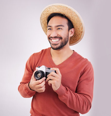 Travel, camera and happy asian man on holiday, adventure and photography on white background. Smile on face, tourism and Indian photographer or journalist on vacation, happiness on journey in studio.の写真素材