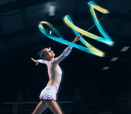 Ribbon gymnastics, woman and smile in motion blur of dancer, talent show and competition in dark arena. Happy female athlete, rhythmic movement and dancing for action, creative sports and performanceの写真素材