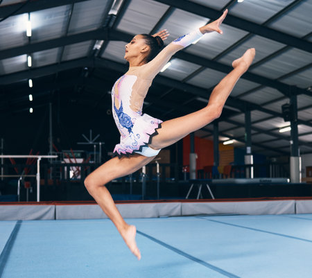 Woman, gymnastics and jump for performance, flexible dance skill and sports competition. Female, rhythmic movement and stretching body in action, creative talent and motion with agility in arena showの写真素材