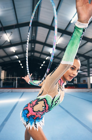 Woman, gymnastics and hoop for competition, sports training and dancing action in arena. Female, rhythmic movement and dancer with spinning ring for creative talent, solo concert or event performanceの写真素材