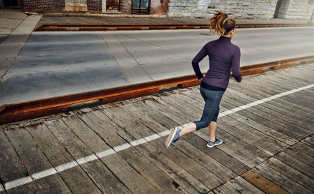 No day goes by without a run. Rearview shot of an unrecognizable young woman running through the city.の写真素材