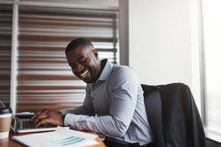 Hes having a great time in the office. a handsome businessman laughing while working in his corporate office.の写真素材