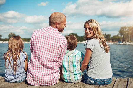 Thankful, grateful and blessed. a family on a pier while out by the lake.の写真素材