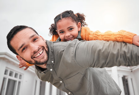 Portrait, piggy back and happy man with child in yard of new house, happiness and security at family home. Homeowner, father and girl bonding in backyard together with love and outdoor fun on weekendの写真素材
