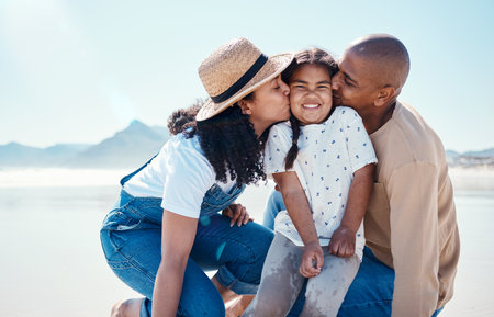 Black family, children and beach with parents kissing their daughter outdoor in nature on the sand by the ocean. Kids, love or summer with a mother and father giving a kiss to their female childの写真素材