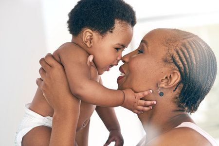 Relax, touch and nose with mother and baby for bonding, affectionate and connection in family home. Kindness, happiness and smile with black woman holding child for positive, growth and supportの写真素材