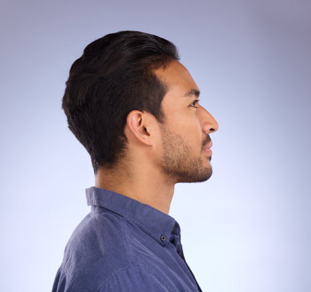 Profile, head and thinking with a man in studio on a gray background looking thoughtful or contemplative. Idea, side and face with a handsome young male contemplating a thought on a color wallの写真素材