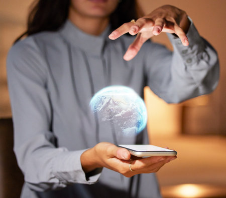 Woman, hands and phone with 3D hologram of globe for global communication, networking or technology at night. Hand of female holding smartphone with holographic earth for futuristic tech innovationの写真素材