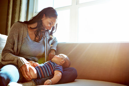 Such a tiny person, such a lot of love. a young woman bonding with her baby boy on the sofa at home.の写真素材