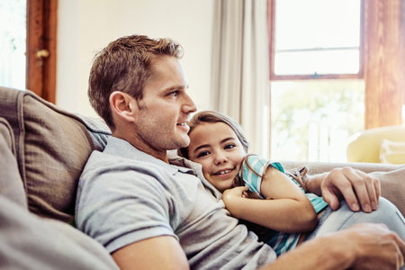 Cosy in her fathers arms. a father and his little daughter bonding together at home.の写真素材