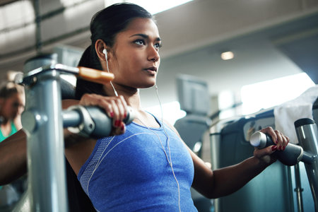 Theres no workout she cant crush. a young woman working out with a chest press at a gym.