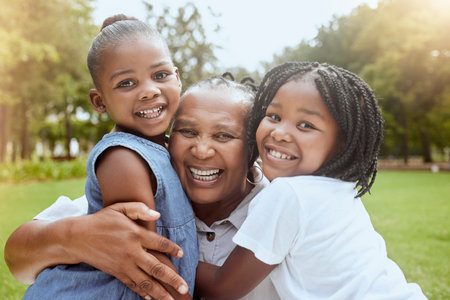 Park, black family and portrait of children with grandmother bonding, smiling and having fun. Summer, love and grandma embrace and hug girls for quality time on weekend, holiday and vacation outdoorsの写真素材