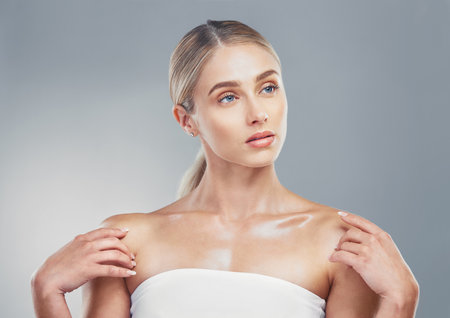 Beauty, skincare and woman model with a glow while advertising cosmetic, makeup or dermatology product on grey studio background. Face of girl posing for health, wellness and shine on skin and bodyの写真素材