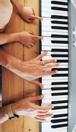 Piano, top view and hands of kid learning with father in home, playing or bonding together....