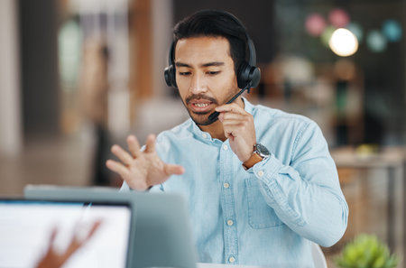Asian man, call center and consulting with headphones on laptop in customer service or desktop support at office. Male consultant agent talking with headset on PC for telemarketing or online adviceの写真素材