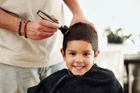 Portrait, kid and shaving hair at barber for grooming, cleaning and trim. Smile, face and happy boy or child getting a haircut with electric shaver of hairdresser at salon for new look and hairstyle.の写真素材