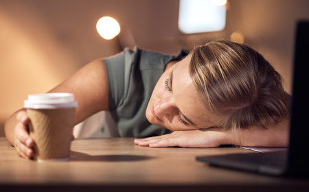 Burnout, sleeping and tired young business woman working at night in office on laptop for deadline, email or proposal. Sleep, exhausted and corporate employee suffering fatigue, workload and pressureの写真素材