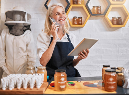 Phone call, honey and tablet with woman in store for natural product, organic and grocery shopping. Retail, health and food ingredient with small business owner with communication and technologyの写真素材