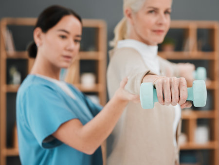 Senior woman, dumbbell and physiotherapy rehabilitation nurse help for fitness and muscle support. Healthcare physiotherapist with hand of elderly patient for physical therapy and stretching exerciseの写真素材