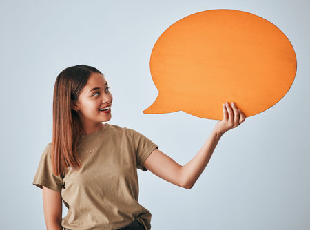 Speech bubble, smile and woman with mockup in studio isolated on a white background. Social media, poster and happy girl with billboard for voice, opinion or branding, marketing or advertising space.の写真素材