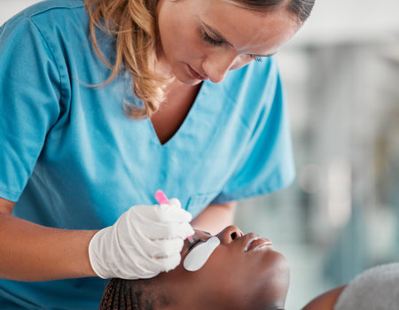 Spa woman, face and tweezers for eyelash extension, medical application or beauty salon healthcare. Cosmetics process, wellness service and relax African client, customer or patient for luxury lashesの写真素材