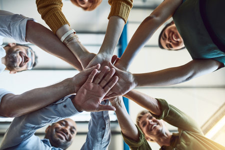 The supportive team is a strong team. Low angle shot of a group of colleagues joining their hands in solidarity at work.の写真素材