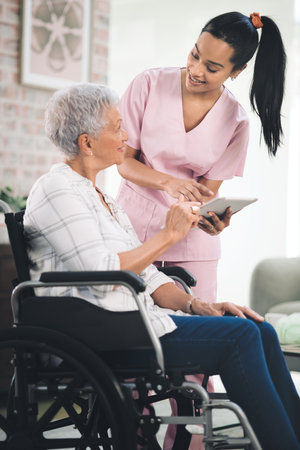 Ill be strong for you. a young nurse sharing information from her digital tablet with an older woman in a wheelchair.の写真素材