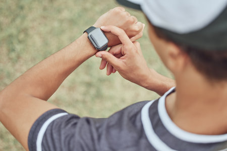 Fitness, man and watch monitoring sports workout, exercise or training in the nature outdoors. Active male in healthy sport checking wrist technology for time, cardio or pulse in athletic exercisingの写真素材