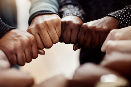 Closeup shot of a group of university students joining their hands together in unity.