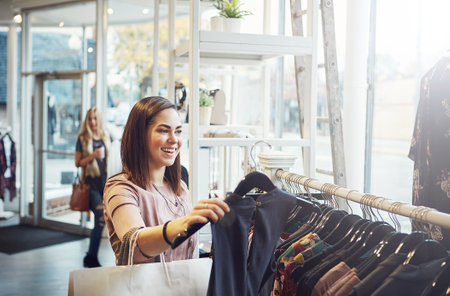 a young woman holding up an item that she picked out in a clothing store.の写真素材