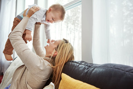 a happy young mother playing with her baby boy at home.