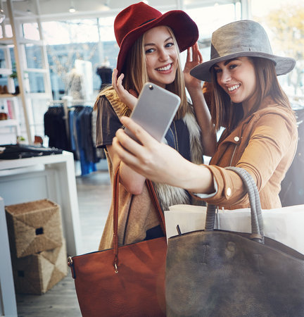 two young girlfriends snapping selfies while out on a shopping spree.の写真素材