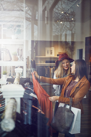 This special wont come around again. two best friends out shopping in a clothing store.の写真素材