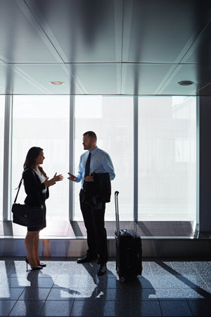 Going places with business. two businesspeople talking together in an airport.の写真素材