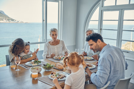 Family, generations and food, eating together in family home by the beach, healthy meal, nutrition and bonding. Big family, parents with grandparents and children eat at house by coast of Australia.の写真素材
