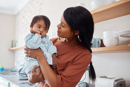 Love, down syndrome and mother and baby in a kitchen, embrace and bonding while talking in their home. Child development, kids and and disability care by parent being loving and caring with cute sonの写真素材